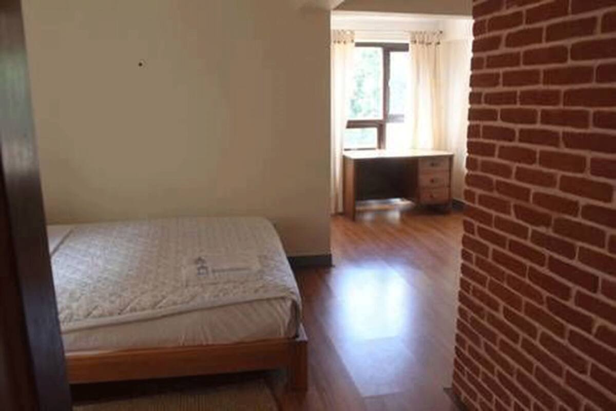 Un dormitorio con cama, escritorio y ventana con cortinas.