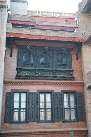 A traditional building with ornate wooden window frames and a red awning. - Lalit Heritage Home (Lalitpur)