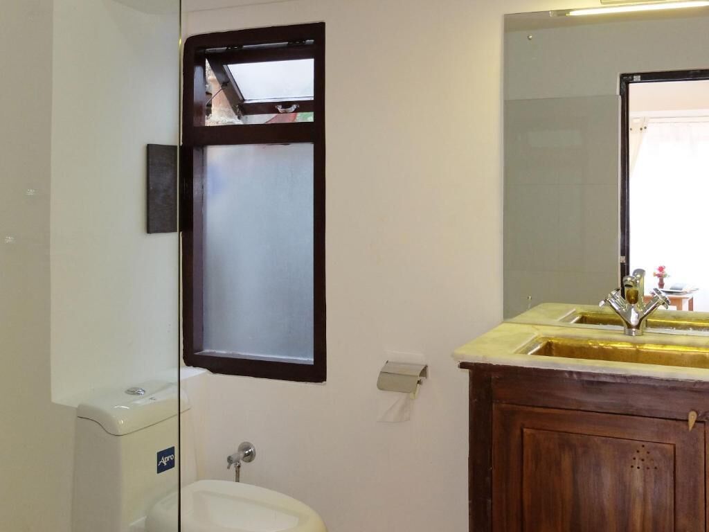 A bathroom with a toilet, sink, and mirror.