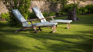 Two lounge chairs with wooden frames and cushioned seats, positioned on a well-maintained lawn with a stone wall and greenery in the background. - Lanes Hotel (Yeovil)