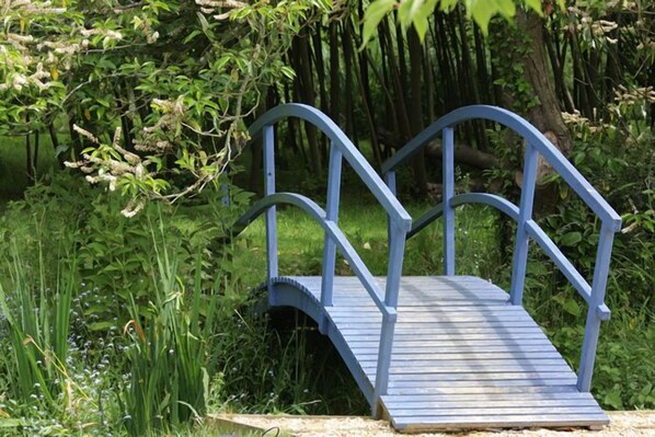 A blue wooden bridge with railings in a lush, green environment. - Lanes Hotel (Yeovil)