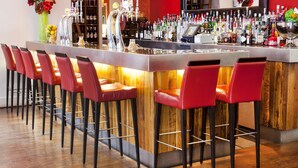 A bar area with a long counter, multiple bar stools, and a variety of bottles and glasses. - Lanes Hotel (Yeovil)