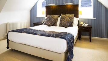 A bedroom with a large bed, two bedside tables, a nightstand, a window with a view, and a radiator.