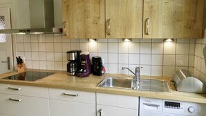 A kitchen with wooden cabinets, a stainless steel sink, a Bosch washing machine, and a coffee maker. - Ferienwohnungen Matthias Zacharias (Würzburg)