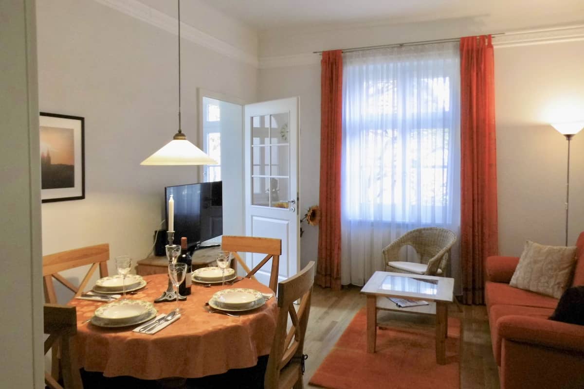A dining area with a table set for four, a television, and a door leading to another room.