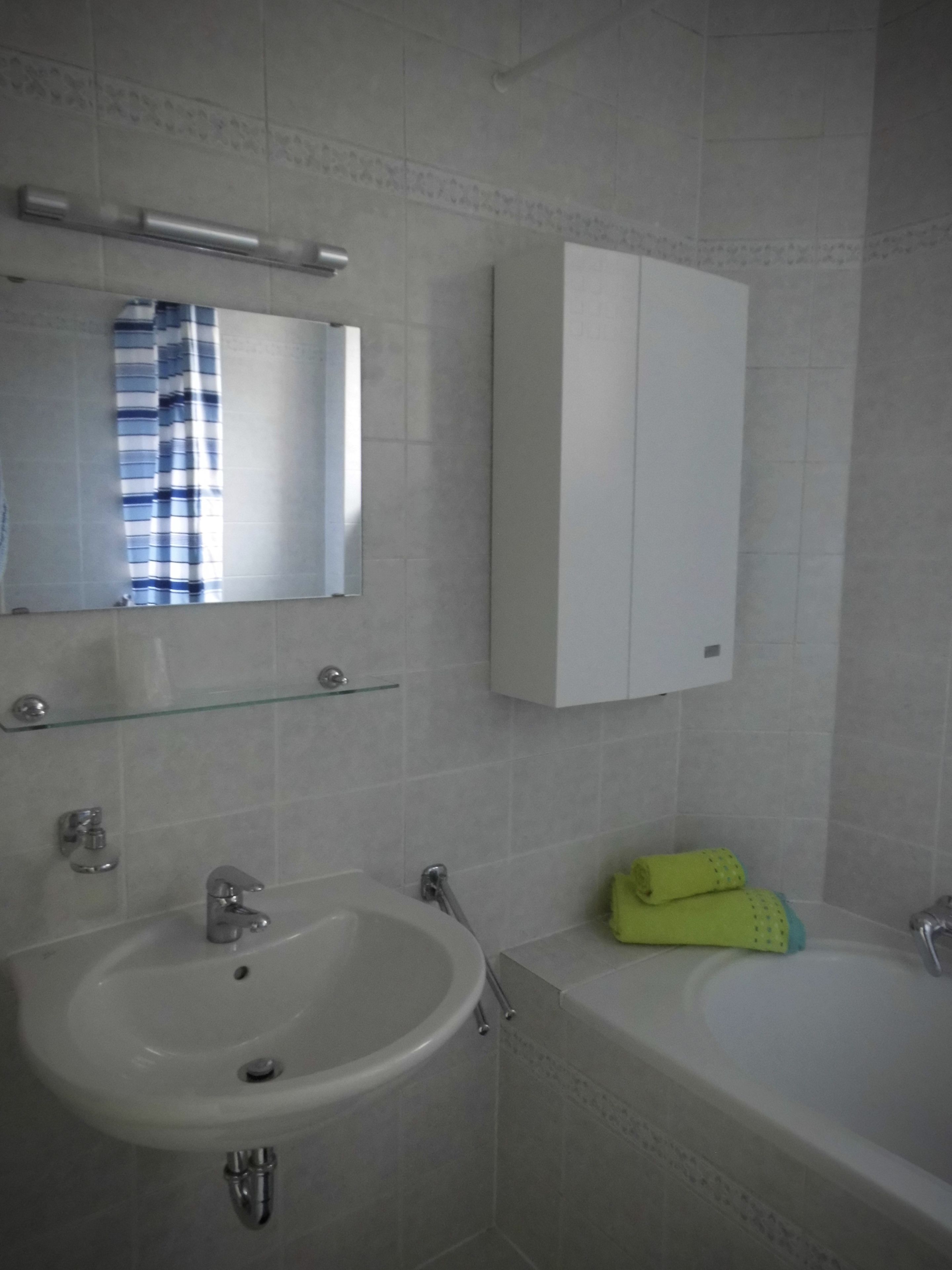 A bathroom with a sink, mirror, cabinet, and bathtub.