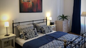 A bedroom with a bed, bedside tables, a lamp, a potted plant, and a painting on the wall. - Ferienwohnungen Matthias Zacharias (Würzburg)
