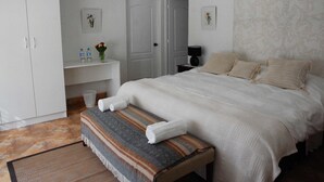 A bedroom with a large bed, a bench, a bedside table with a lamp, and a wardrobe. - Hotel Los Palomos (Lunahuana)