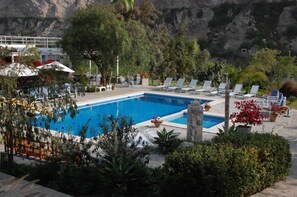 A pool area with lounge chairs, a small pool, and surrounding greenery. - Hotel Los Palomos (Lunahuana)