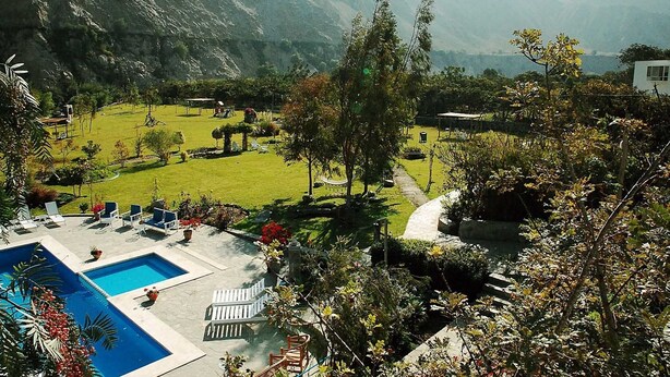 A pool area with lounge chairs and a small garden with a pathway. - Hotel Los Palomos (Lunahuana)