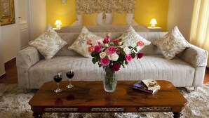 A room with a sofa, a coffee table with a vase of flowers, and two bedside lamps. - Hotel Los Palomos (Lunahuana)