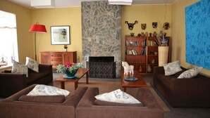 A living room with two brown sofas, a coffee table, a fireplace, a bookshelf, and a red lamp. - Hotel Los Palomos (Lunahuana)