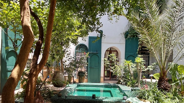 A courtyard with a swimming pool, surrounded by greenery and traditional architecture. - Riad Dar Kleta (Marrakech)