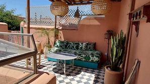 A cozy outdoor seating area with a checkered floor, a cushioned sofa, and a small table. - Riad Dar Kleta (Marrakech)