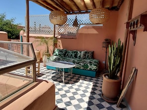 A cozy outdoor seating area with a checkered floor, a cushioned sofa, and a small table. - Riad Dar Kleta (Marrakech)