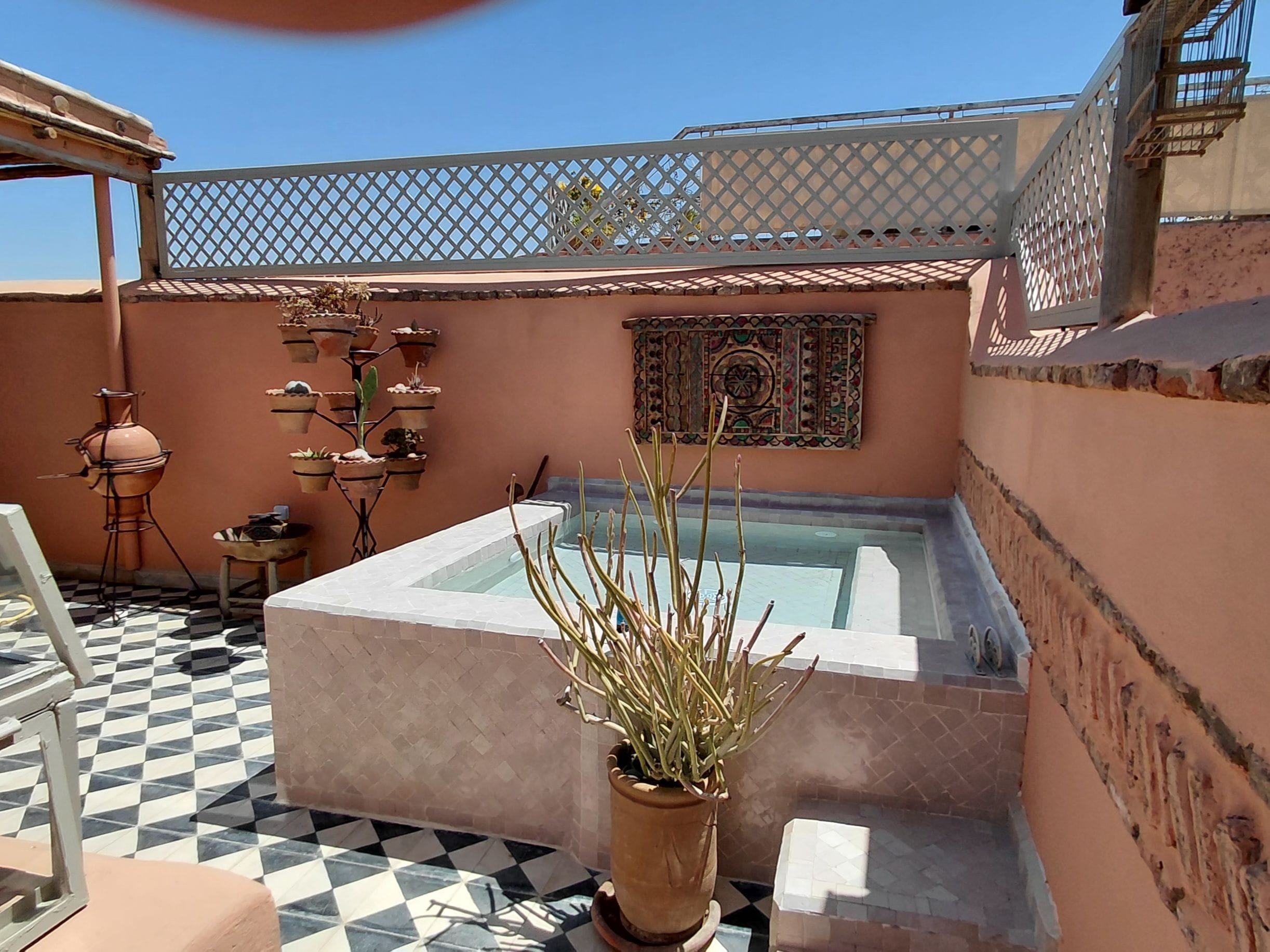 Una terraza en la azotea con suelo a cuadros, un jacuzzi y plantas en macetas.