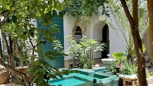 A courtyard with a swimming pool, potted plants, and a traditional building with arched doorways. - Riad Dar Kleta (Marrakech)