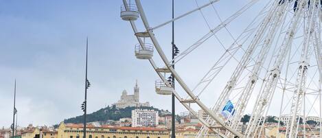 A Ferris wheel with a view of a cityscape and a hill with a church in the background.