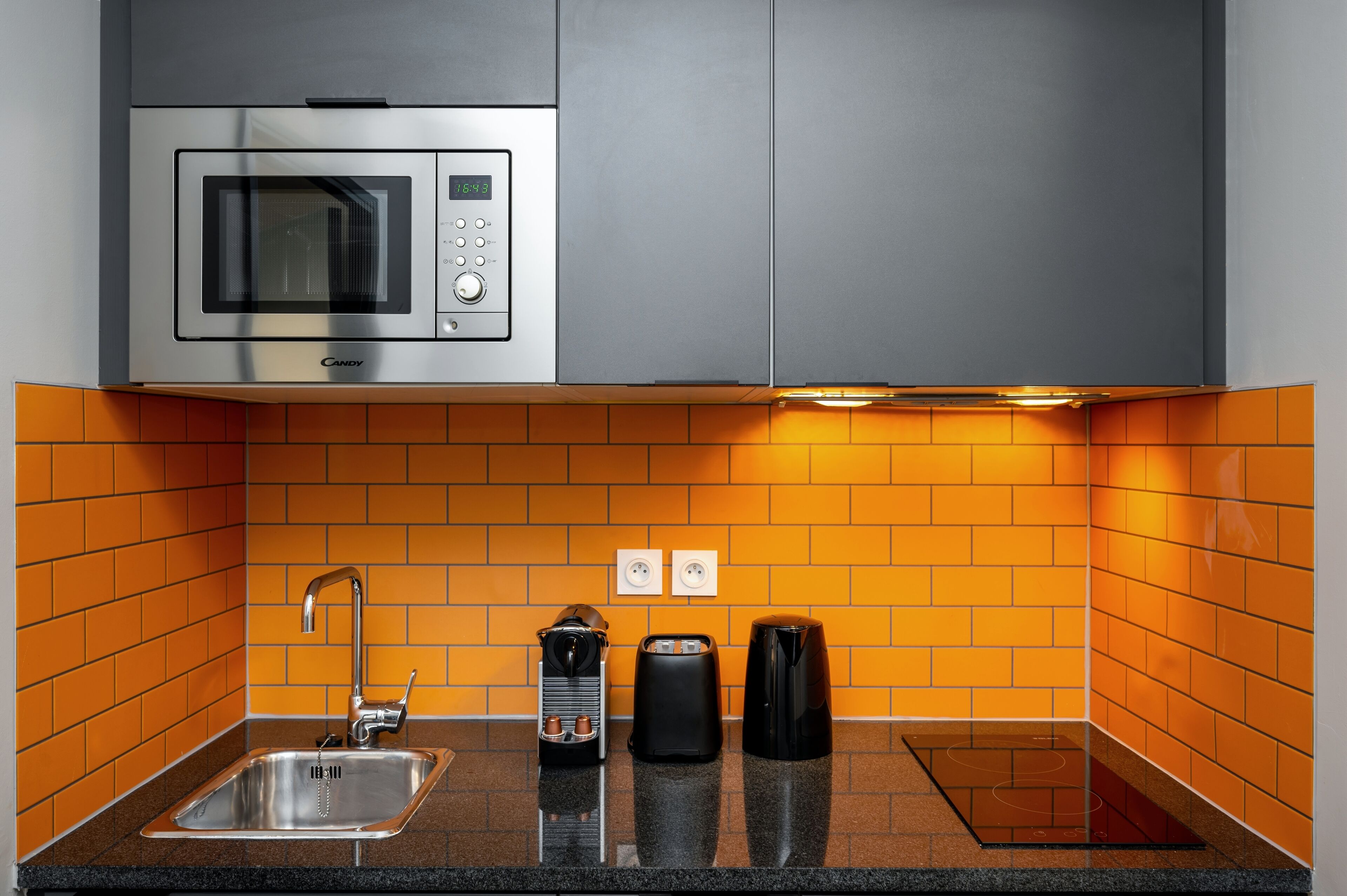 Una cocina moderna con microondas integrado, un lavabo y una cafetera.