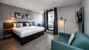 Une chambre d’hôtel moderne, dotée d’un grand lit, de tables de chevet, d’un bureau, d’un canapé et d’œuvres d’art accrochées au mur.