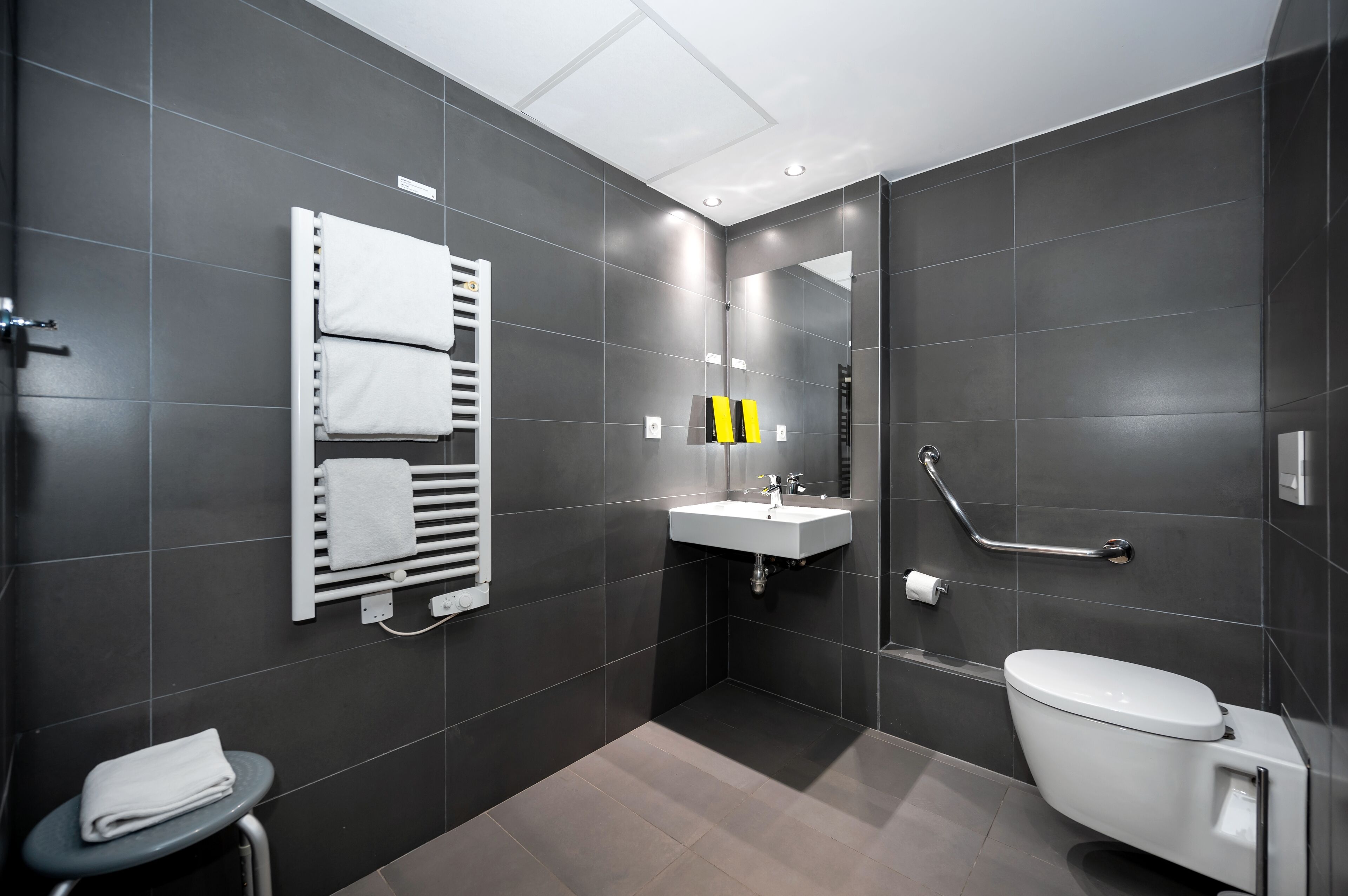 A modern bathroom with a toilet, sink, and towel rack.