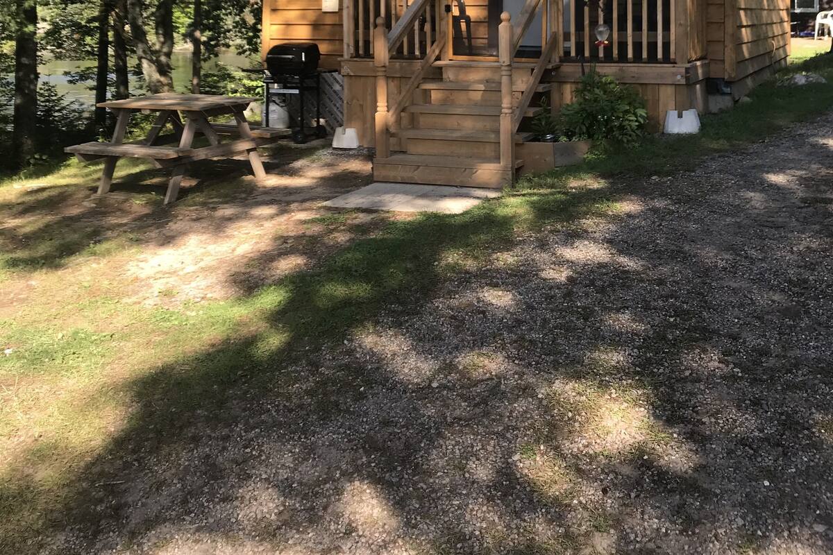 A wooden cabin with a porch, a picnic table, and a grill.