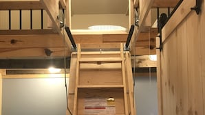 A wooden ladder structure in a kitchen with a stove, a refrigerator, and a patterned rug on the floor. - Longmuir's Hidden Cove Cottage Resort (Addington Highlands)