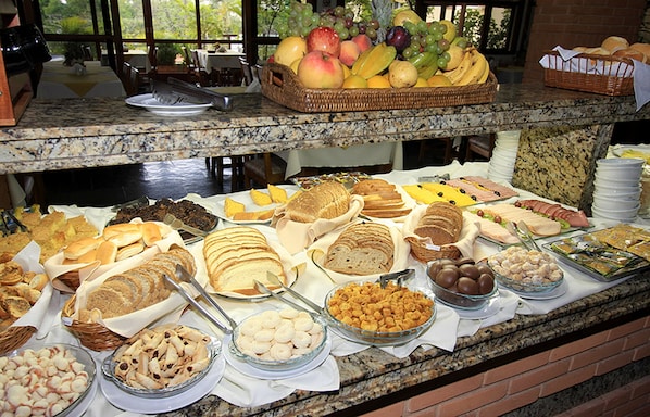 Un buffet proposant une variété d’aliments, notamment des fruits, du pain et des pâtisseries.