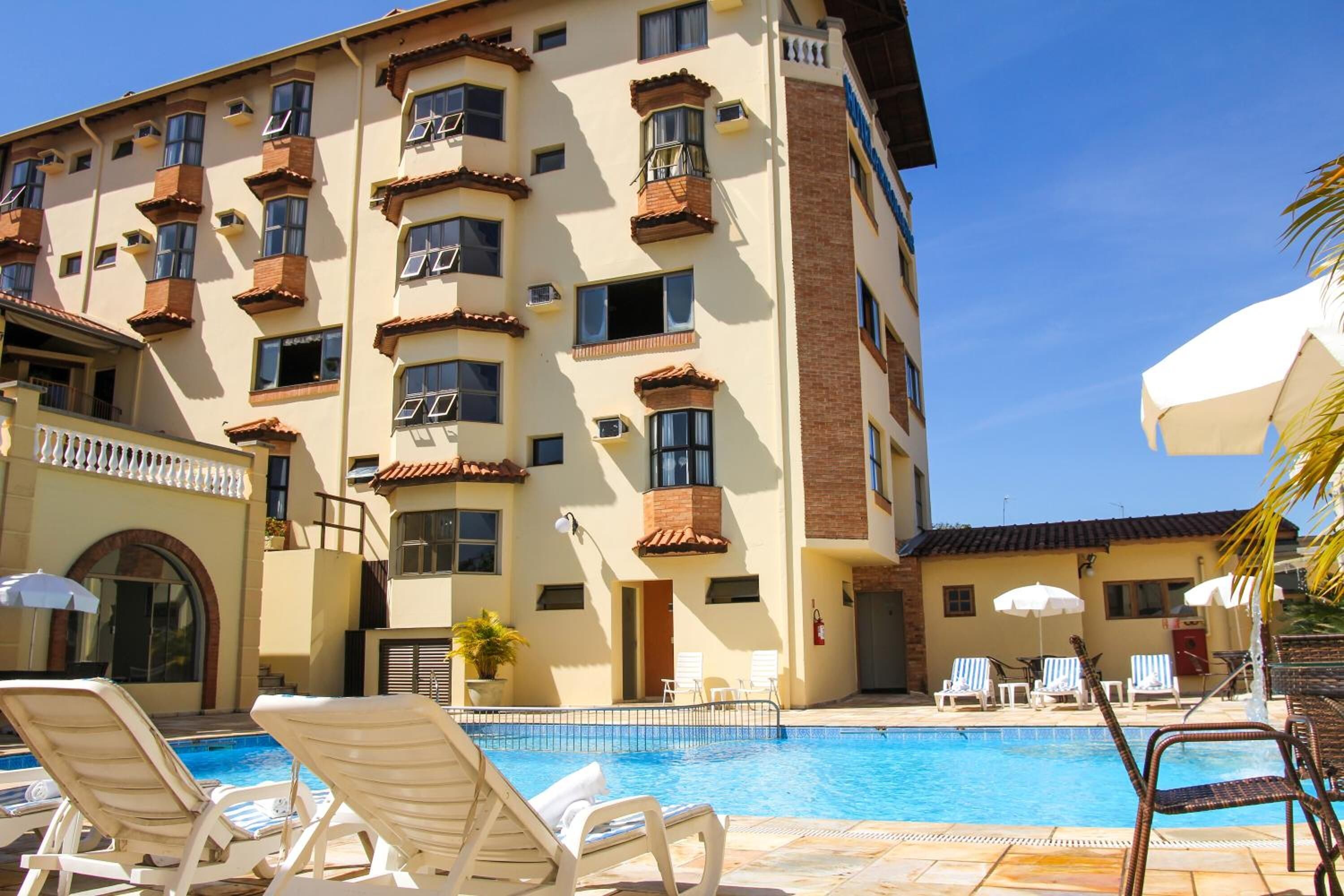 Un hotel con piscina, sillas de sol y sombrillas.