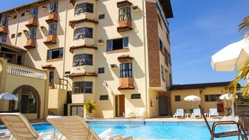 Un hotel con piscina, sillas de sol y sombrillas.