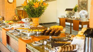 Uma mesa de buffet com diversos alimentos e um arranjo de flores.