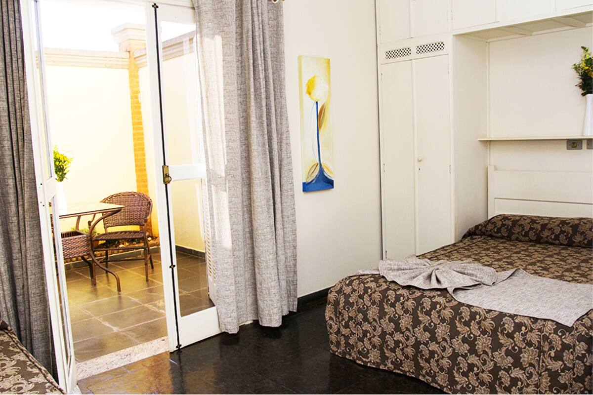 Habitación de hotel con cama, una silla, una mesa y un cuadro en la pared.