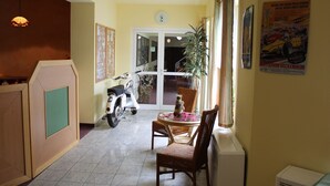 Un comedor con una mesa, sillas, una scooter y una ventana con cortinas.