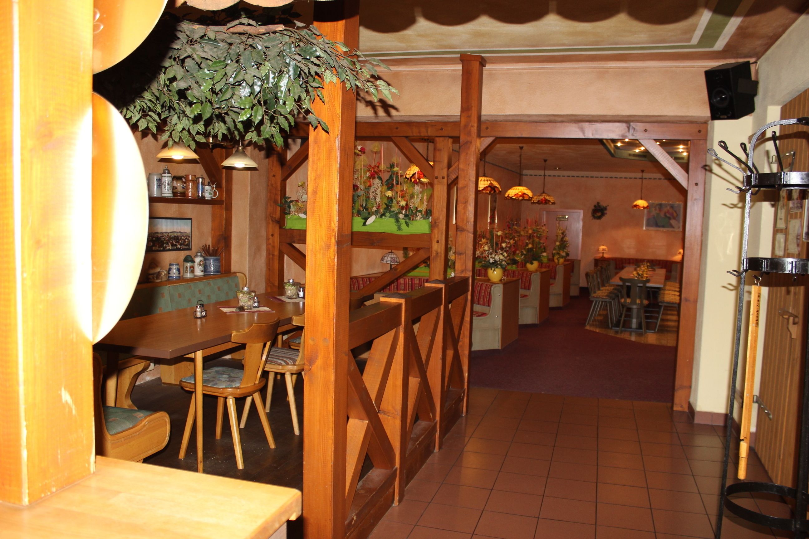 Ein gemütliches Restaurant mit Holzmöbeln, einer hängenden Pflanze und rustikalem Ambiente.