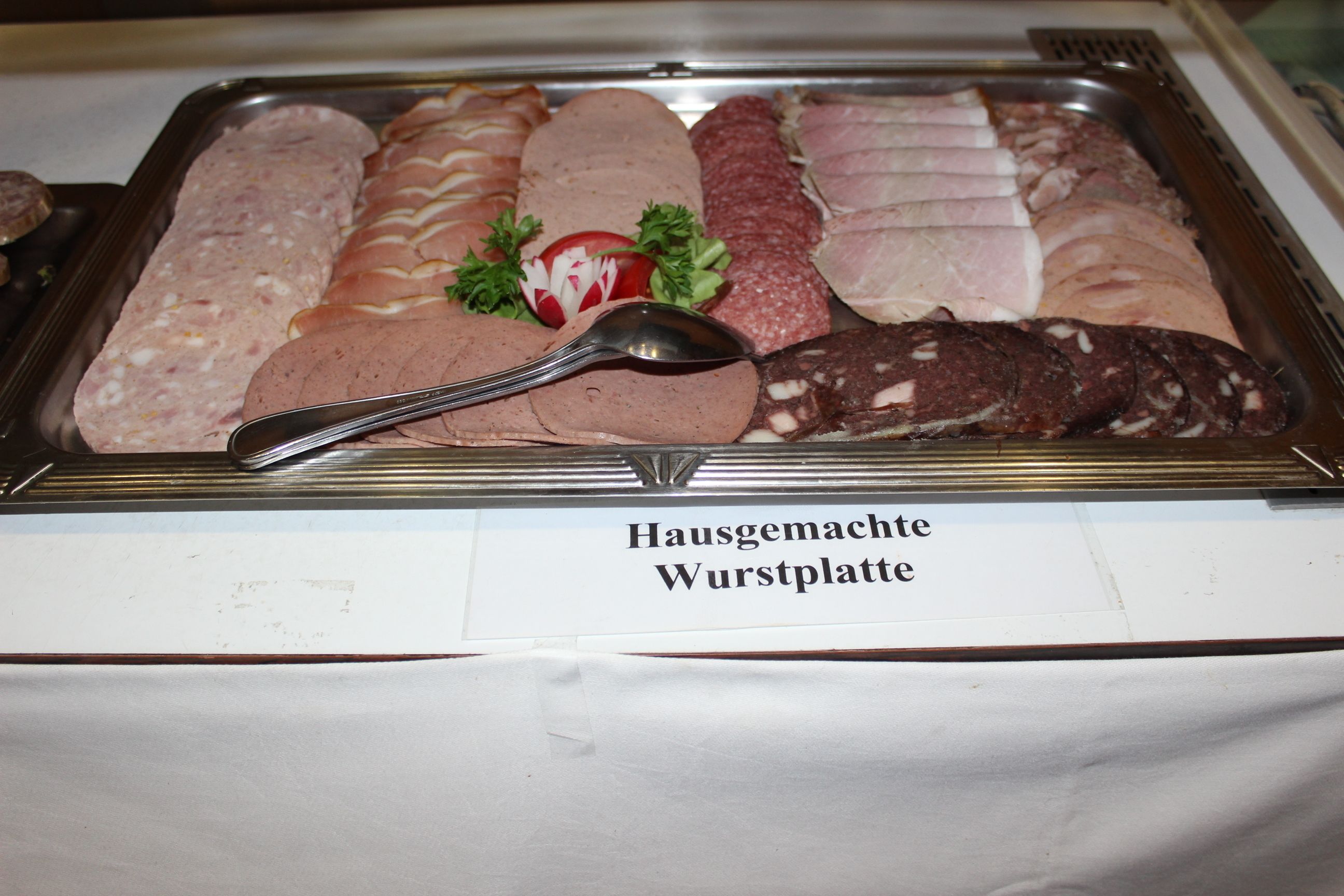 A display of various types of wurst (sausages) with a spoon on top.