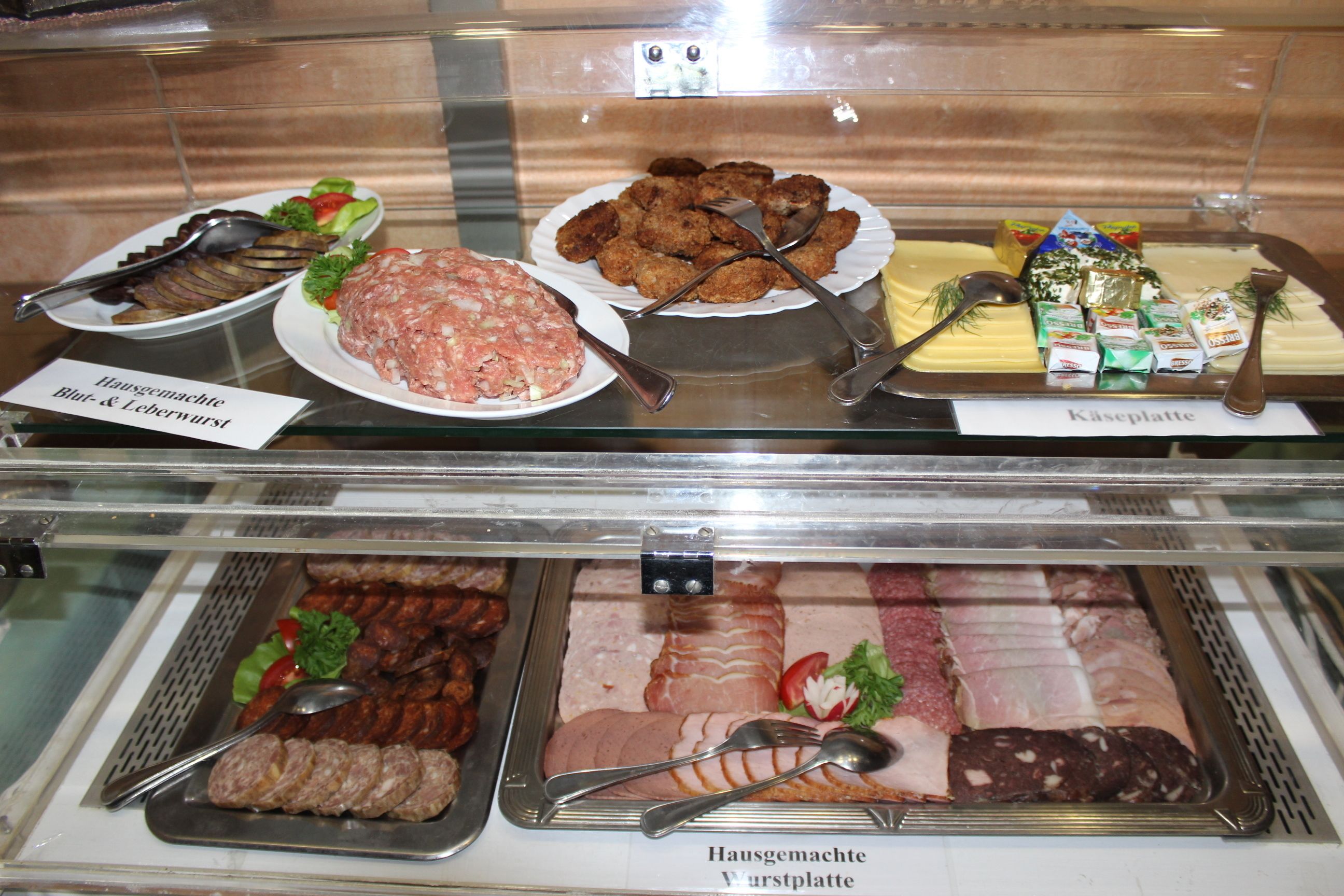 A display case with various food items including meat, cheese, and condiments.