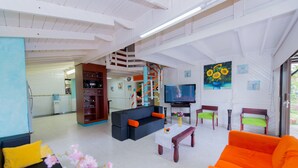 A spacious living area with a sofa, coffee table, and chairs. A staircase leads to an upper level. - Beautiful View Lodging (San Andrés)