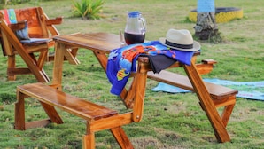 A wooden picnic table with a pitcher of red beverage, a hat, and a colorful cloth. - Beautiful View Lodging (San Andrés)