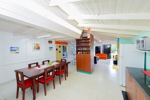 Un comedor espacioso con una mesa de madera y sillas rojas, una cocina con electrodomésticos modernos y un interior luminoso y bien iluminado.