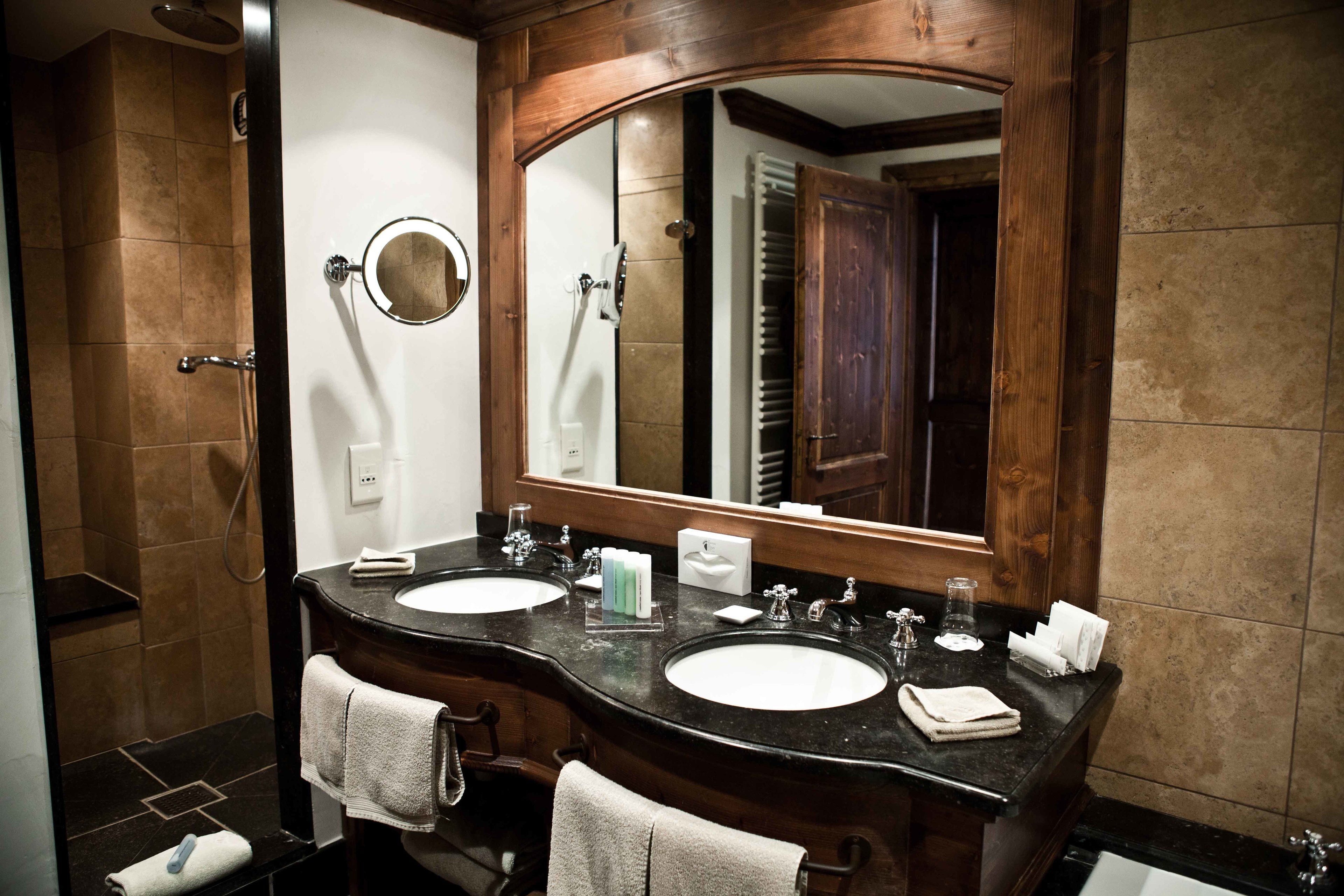 A bathroom with two sinks, a large mirror, and a shower area.