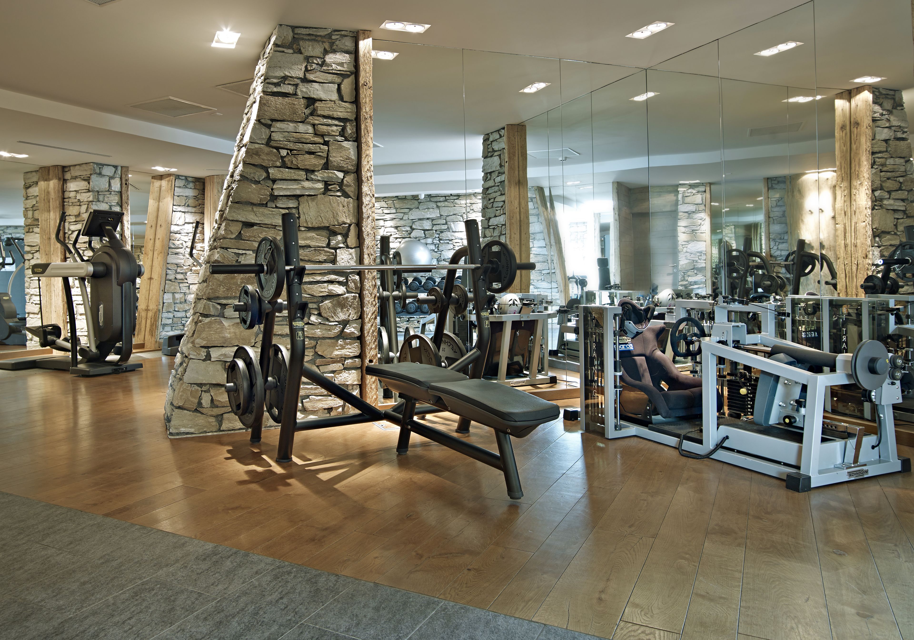 A gym with stone walls, wooden flooring, and various exercise equipment.