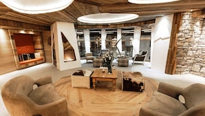 Un interno moderno con un tavolo di legno centrale, zona salotto e camino.