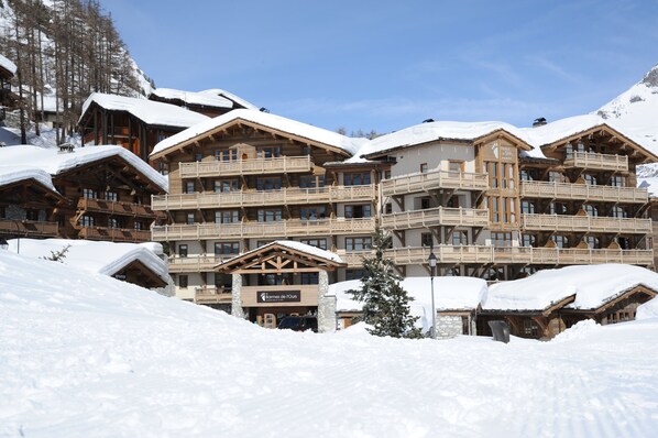 A multi-story wooden lodge with balconies, surrounded by snow-covered terrain.