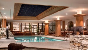 Area piscina con statua di un orso, pilastri in legno e soffitto a cielo stellato.