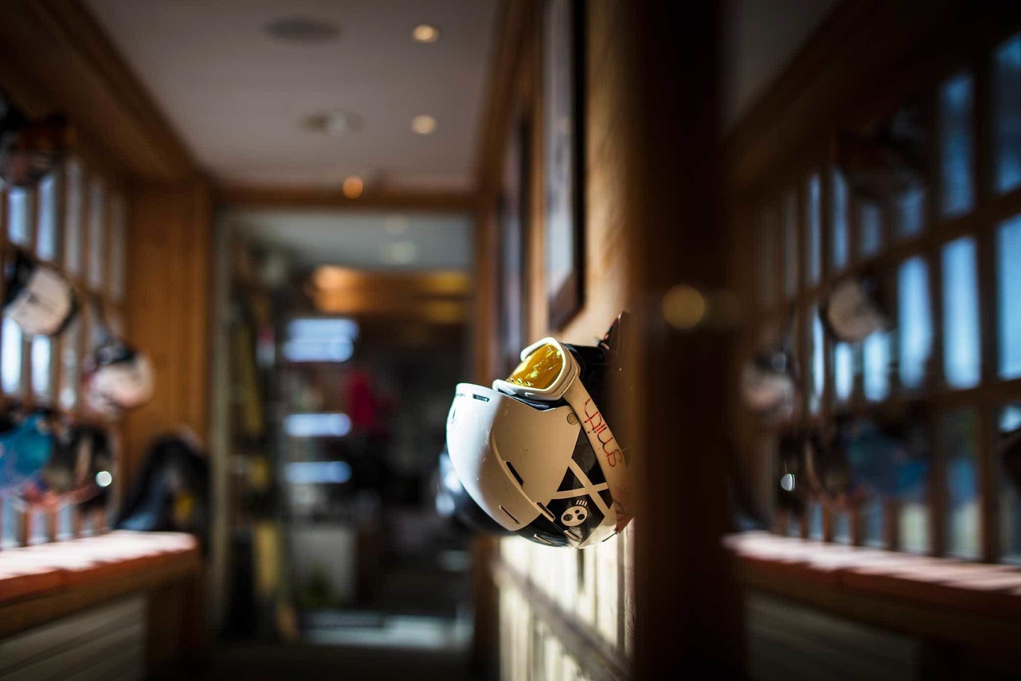 A corridor with a helmet hanging on the wall, wooden paneling, and a television in the background.