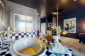 Relax in a stylish space with a large bathtub, mirror, and decorative fountain.