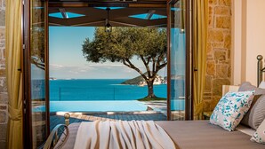 Un dormitorio con una cama, vista al mar y un árbol.