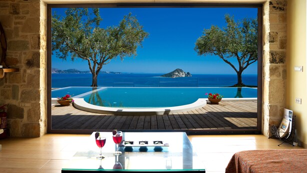 Una habitación con un ventanal grande que da a una piscina, árboles y vistas a la montaña.