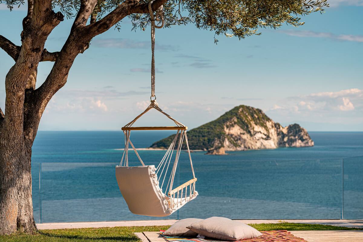 Una hamaca colgada de un árbol, con vistas a la costa, un cielo despejado y una isla distante.