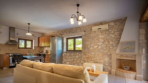 Una cocina moderna con paredes de piedra, una zona de comedor con sofá y una chimenea.